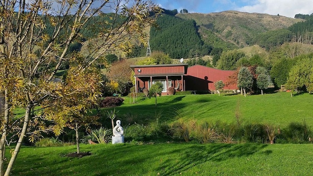 A house with a red roof and a garden with a sculpture. - Matai Huka Boutique Accommodation (Paraparaumu)