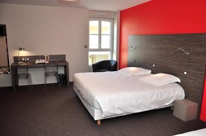 Una habitación de hotel con una cama, un escritorio y una silla, y un ventanal.
