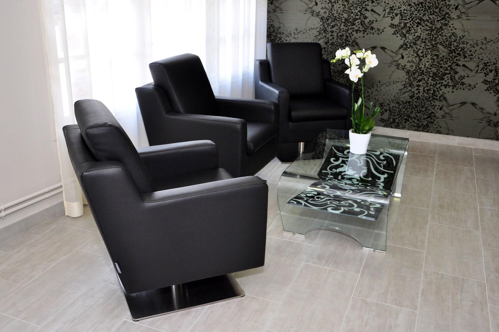 A modern waiting area with black leather chairs, a glass coffee table, and a potted orchid.