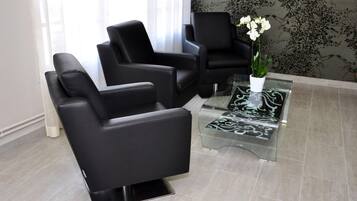 A modern waiting area with black leather chairs, a glass coffee table, and a potted orchid.