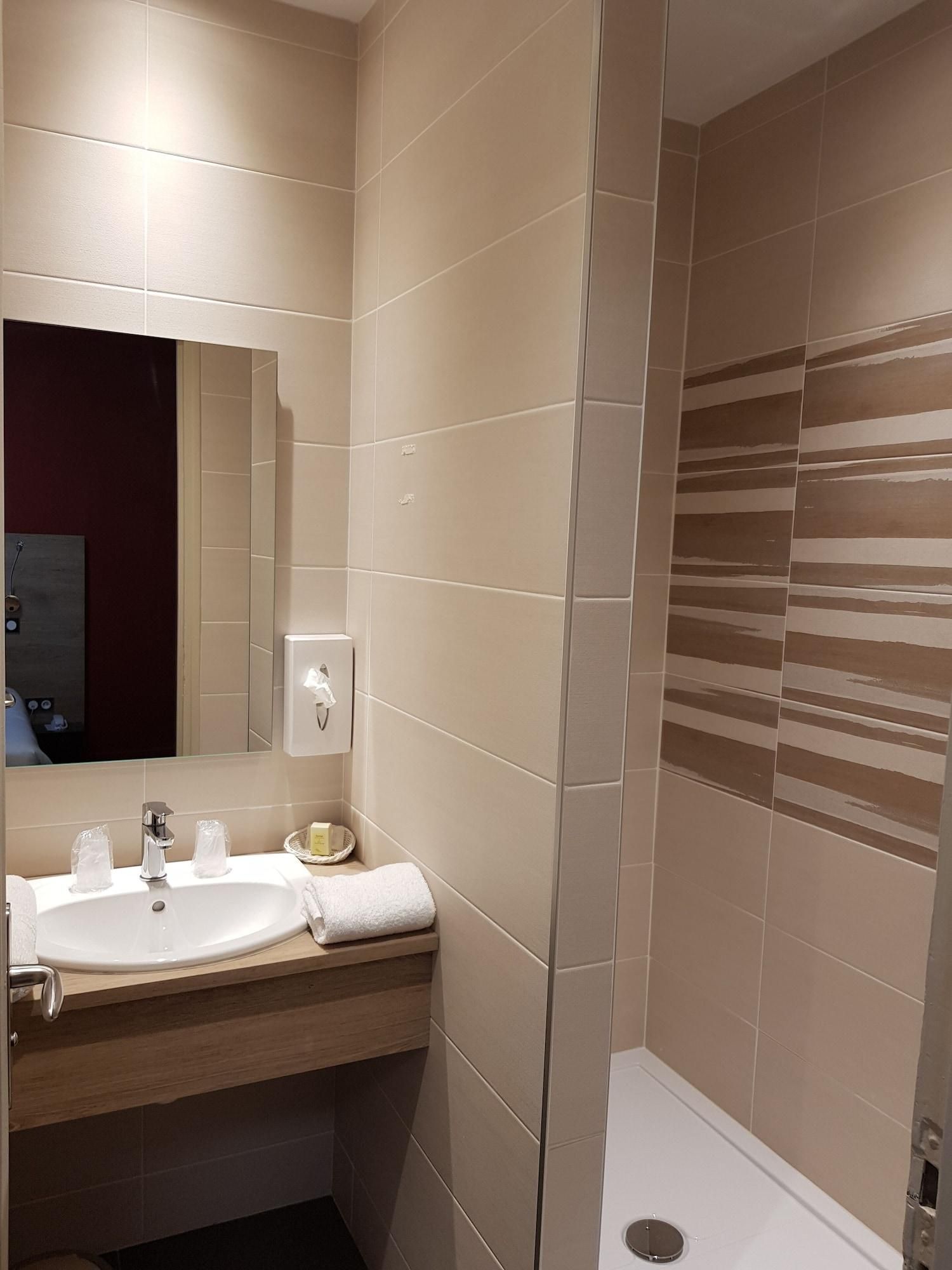 Uma casa de banho moderna com um espelho grande, uma pia e zona de duche.