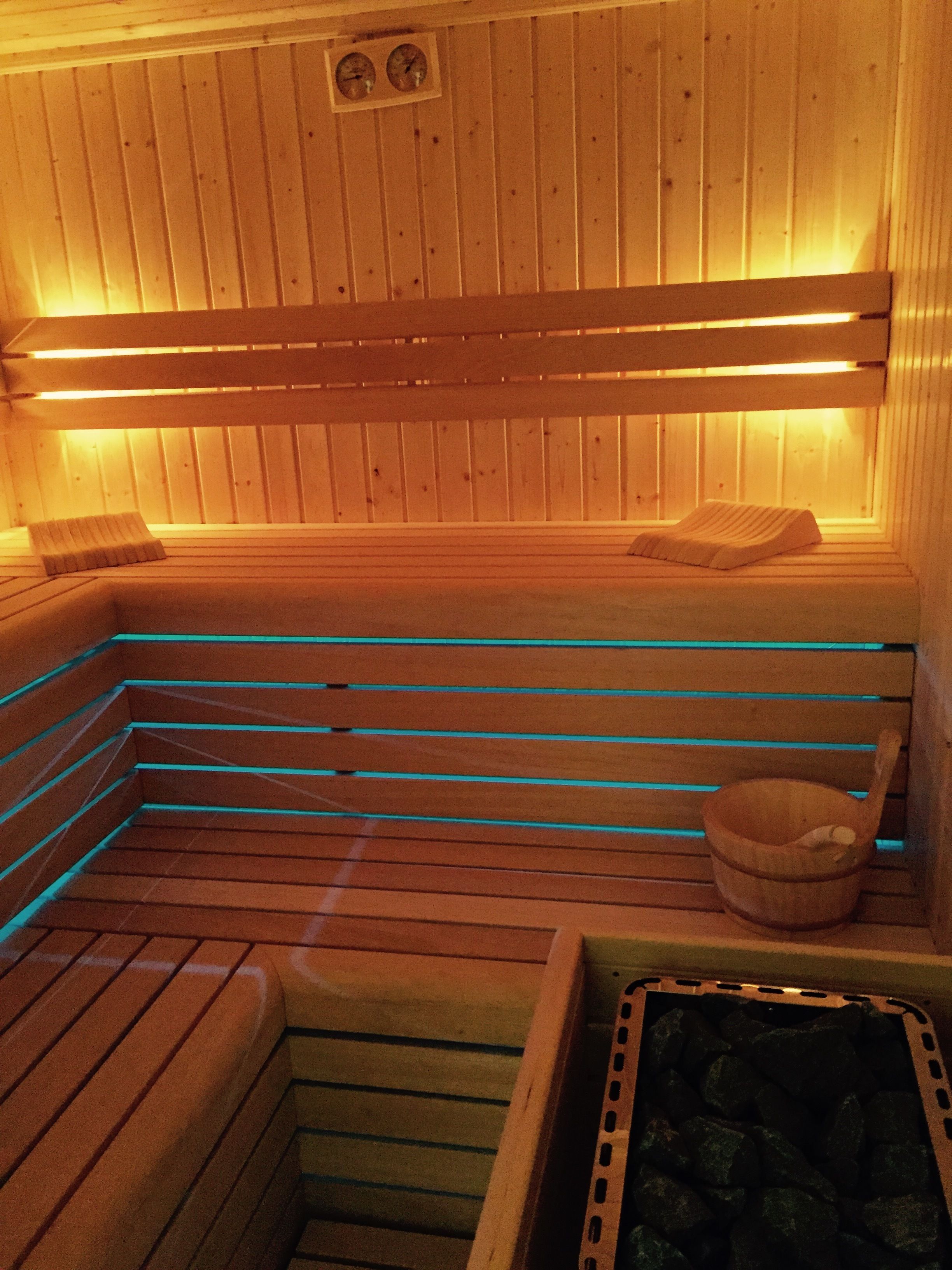 Una sauna con bancos de madera y una pileta de piedra.