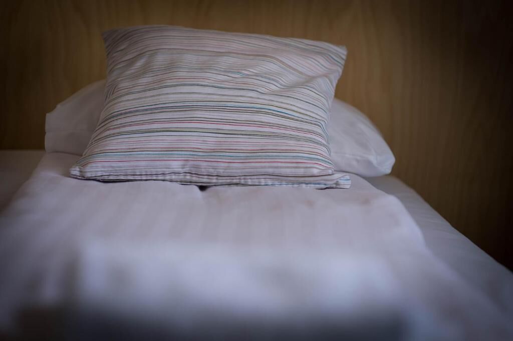 Un lit bien fait, avec un oreiller à rayures et un oreiller uni.