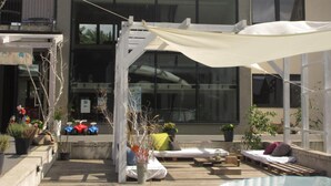 A modern house with a large glass window, a wooden deck, and outdoor seating. - Barcelona Rooms&Restaurant (Stegna)