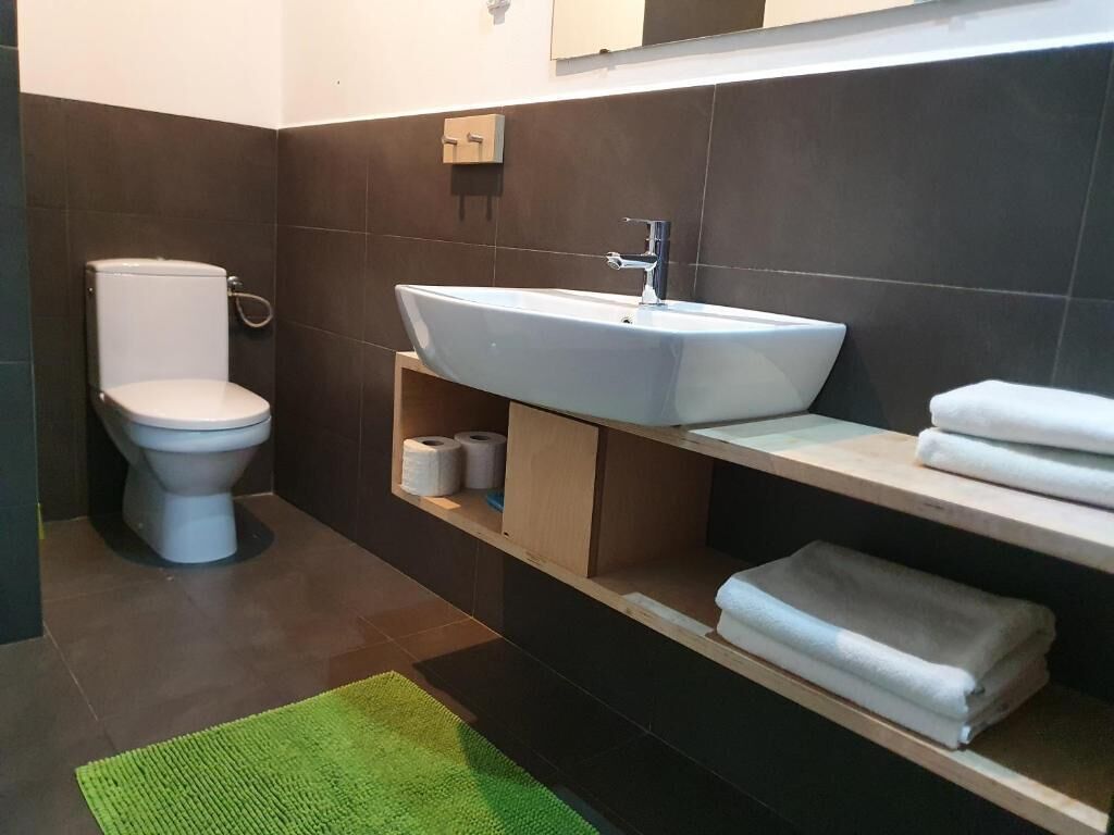 A modern bathroom with a toilet, a sink, and a shelf with towels.