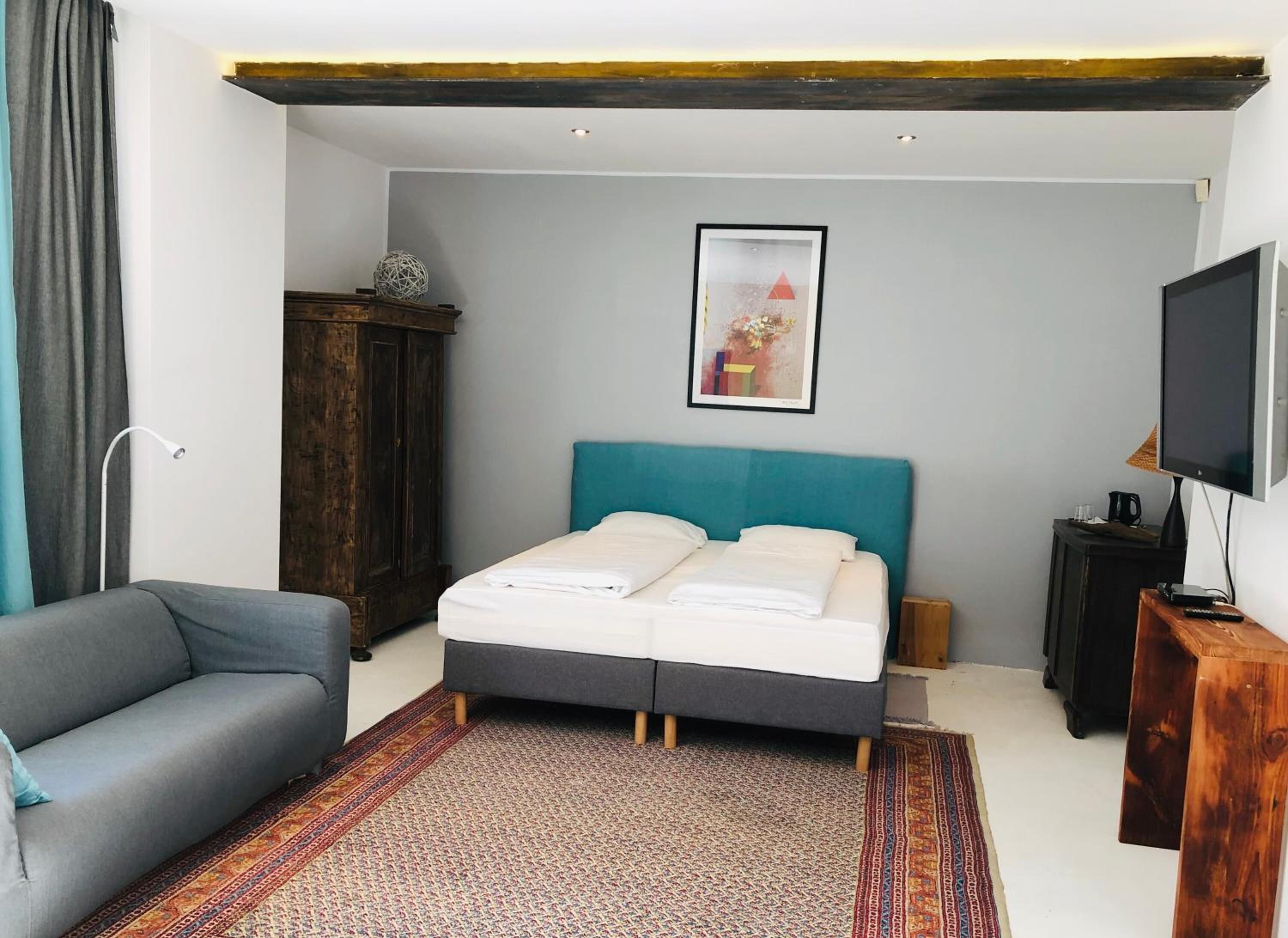 A bedroom with a bed, a sofa, a television, and a cabinet.