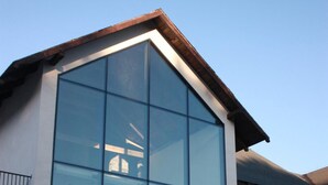 A modern building with large glass windows and a sloped roof. - Barcelona Rooms&Restaurant (Stegna)