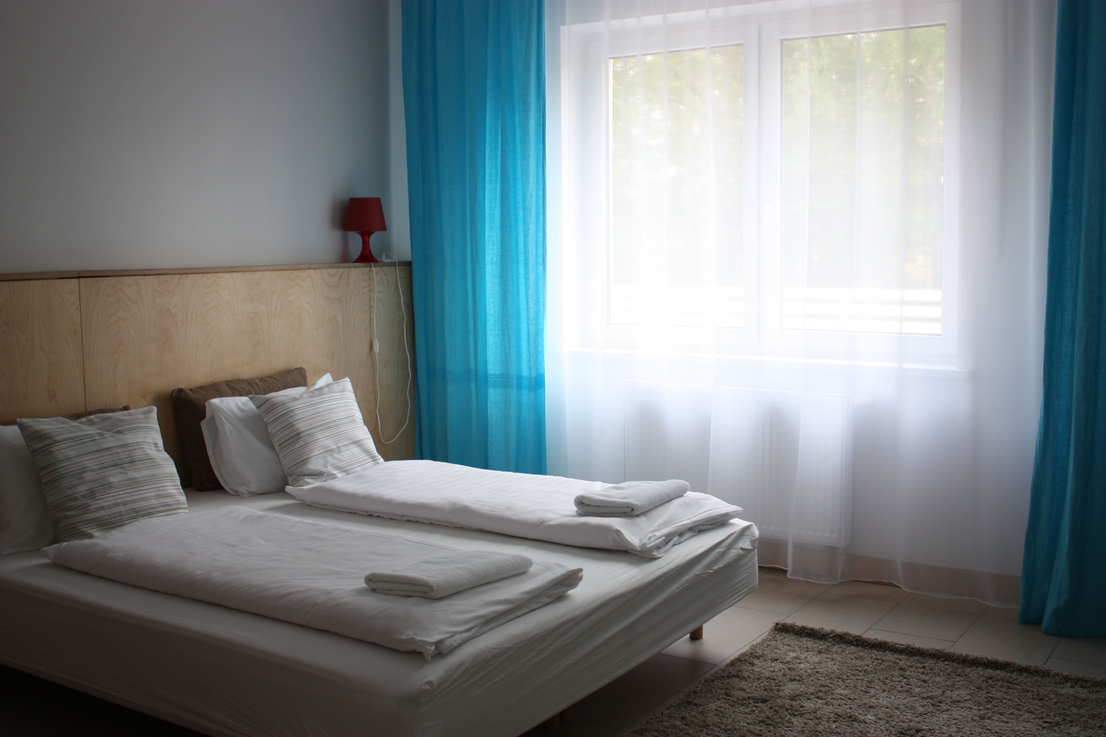 Una habitación de hotel con una cama grande, un cabecero de madera y una ventana con cortinas traslúcidas.