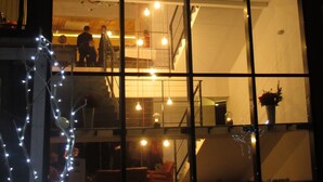 A multi-level building with a large glass facade, interior lighting, and a visible staircase. - Barcelona Rooms&Restaurant (Stegna)