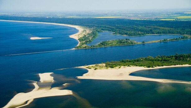 An aerial view of a coastal landscape with a river, sandy beaches, and forested areas. - Barcelona Rooms&Restaurant (Stegna)