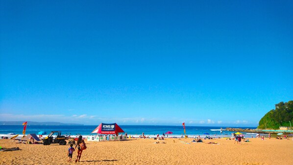 Ein Strand mit einem roten Zelt mit dem Aufdruck 'ICMS' und blauem Himmel.
