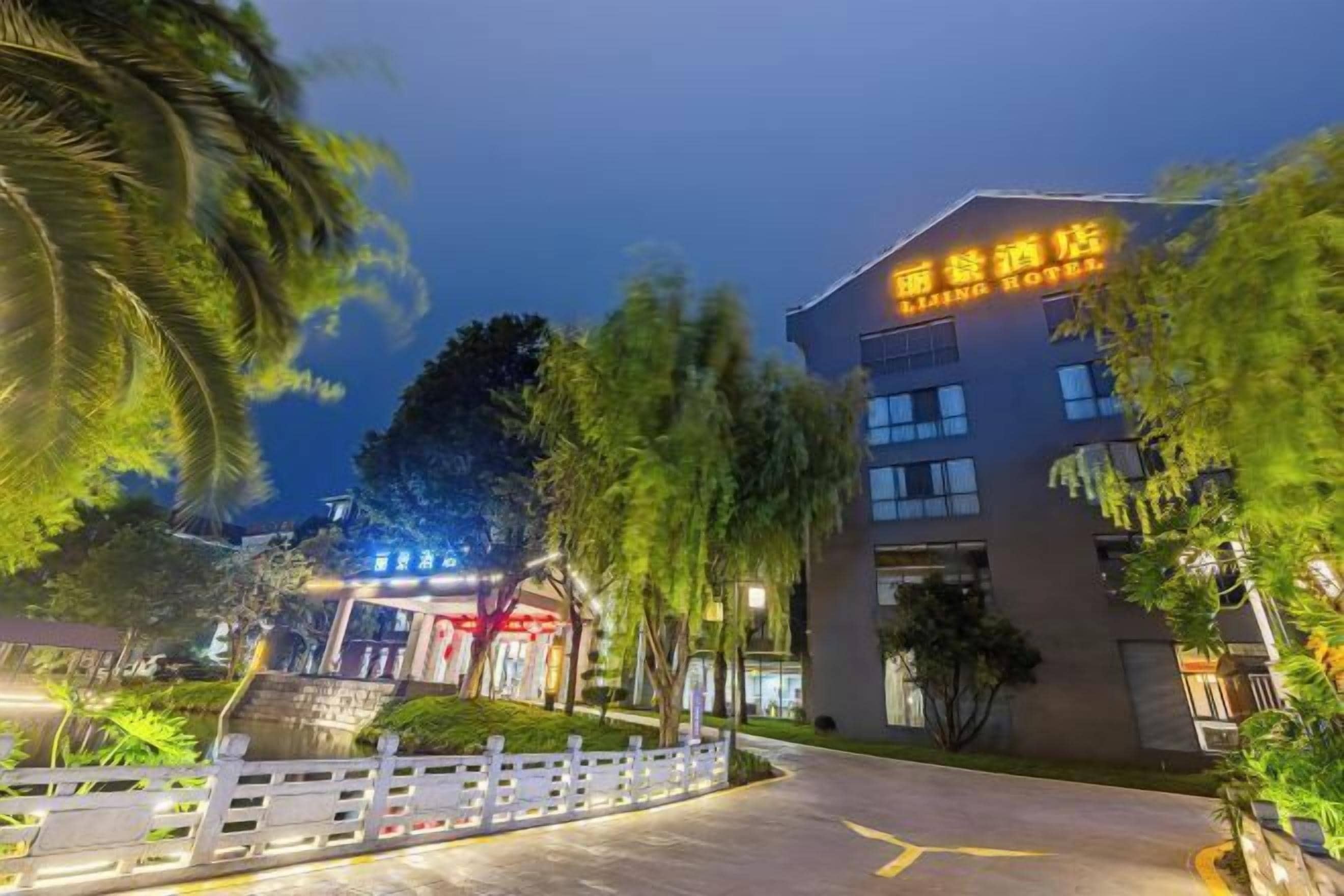 A hotel entrance with a sign reading "Living Hotel" and a well-lit pathway leading to the building.