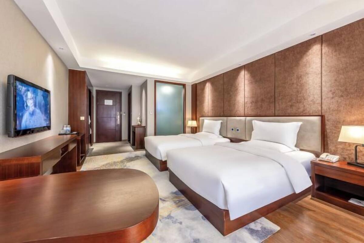 Une chambre d’hôtel avec un grand lit, une télévision, un bureau et une chaise.