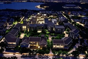 An aerial view of a residential area with modern houses, a waterfront, and a stadium. - Li Jing Hotel Mile (Mile)