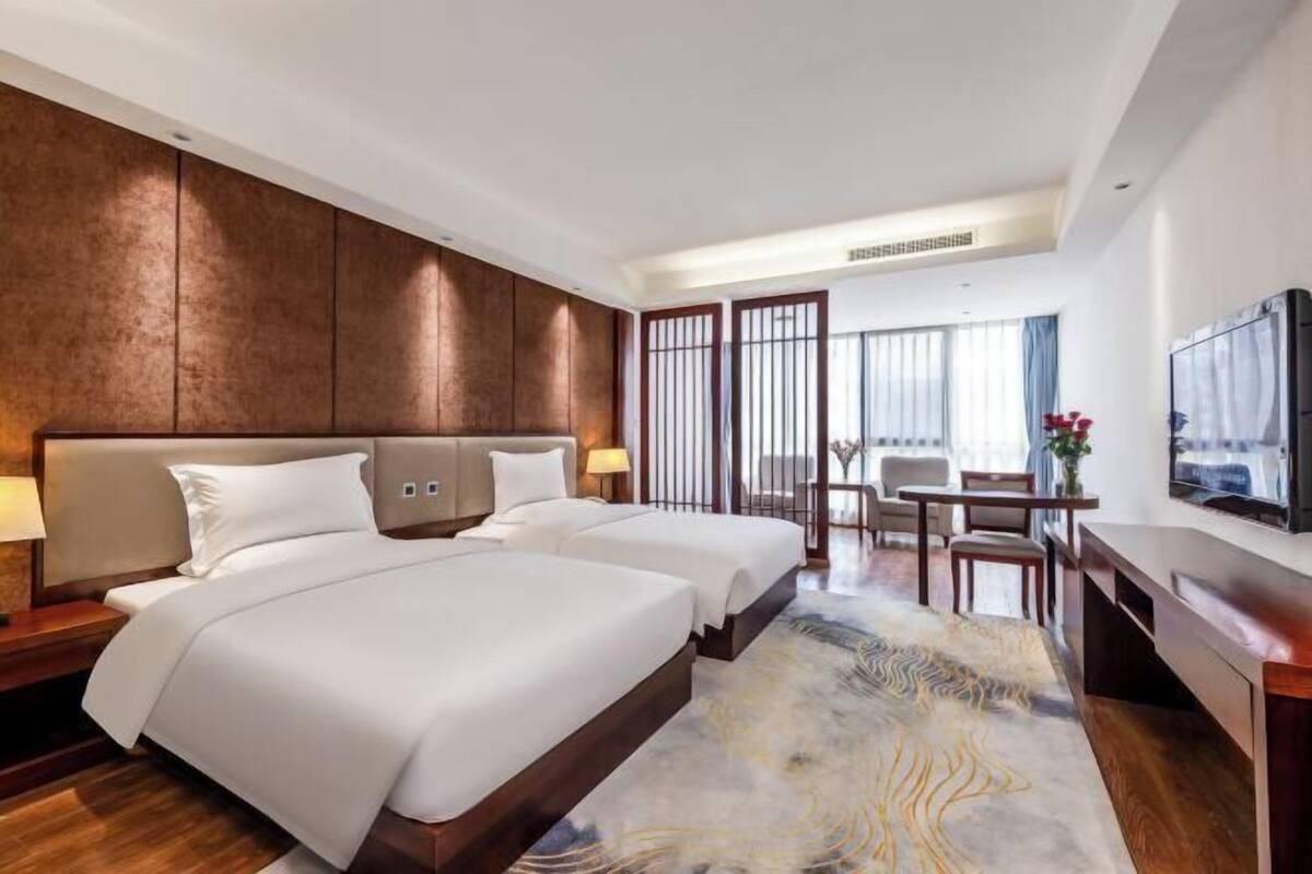 Une chambre d’hôtel avec deux lits, un bureau et une télévision.
