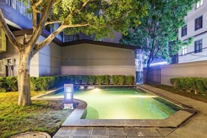Un patio con piscina, rodeado de edificios y árboles.