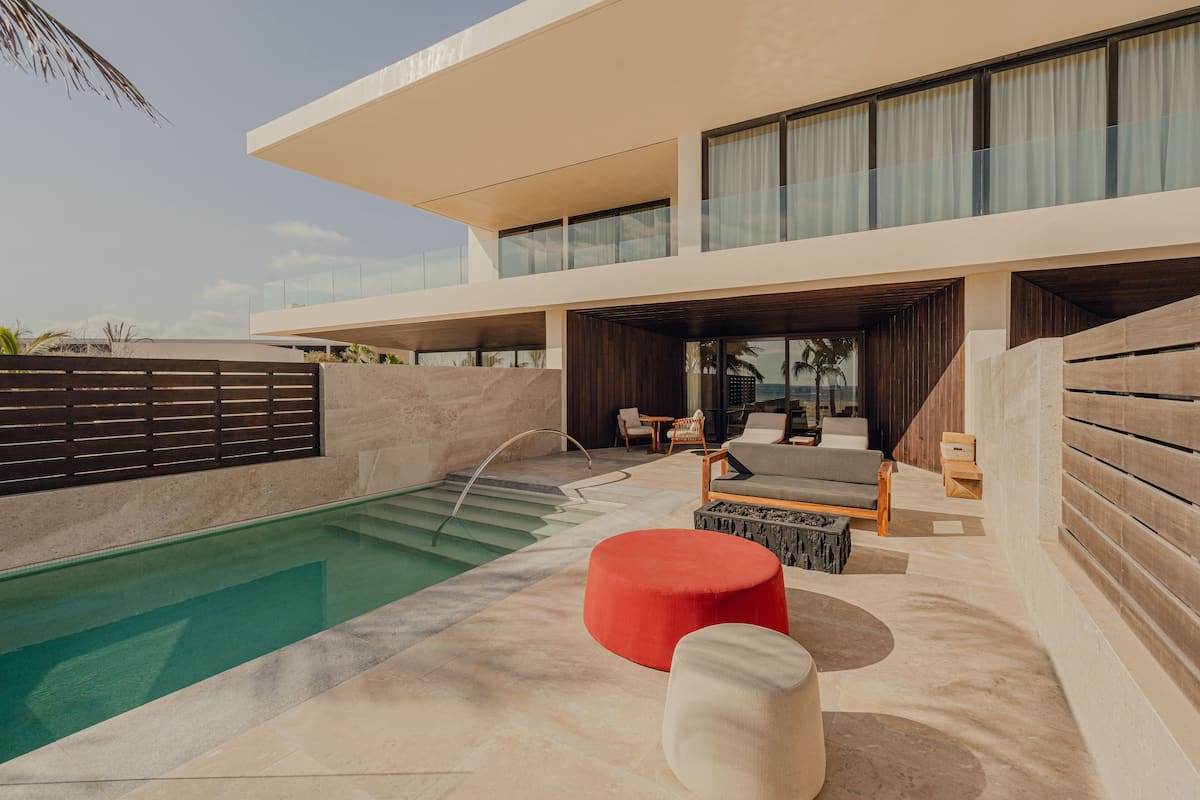 A modern resort with a pool, outdoor seating, and a two-story building.
