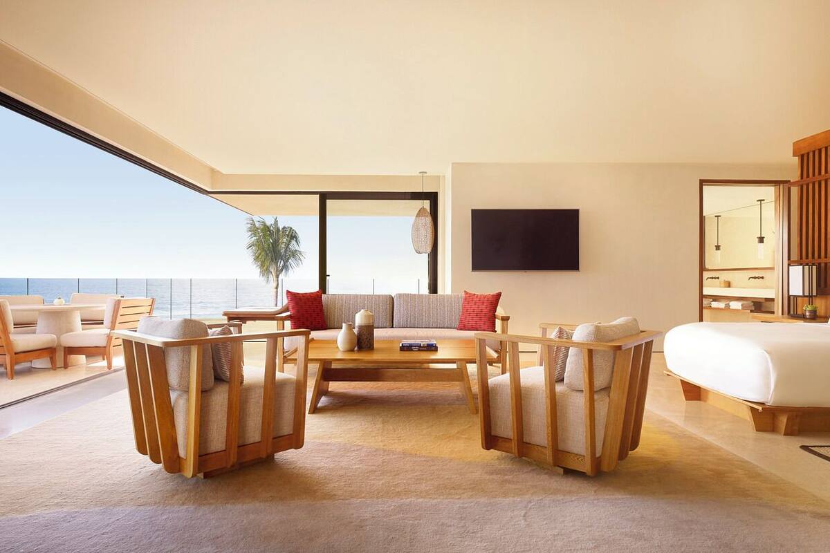 A modern hotel room with a large bed, a sofa, a coffee table, and a TV.