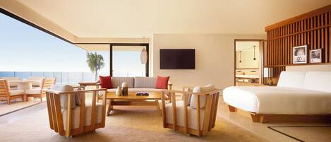 A modern hotel room with a large bed, a sofa, a coffee table, and a TV.