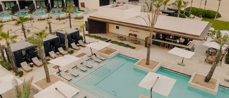 A resort with a large pool, multiple lounge areas, and a bar.