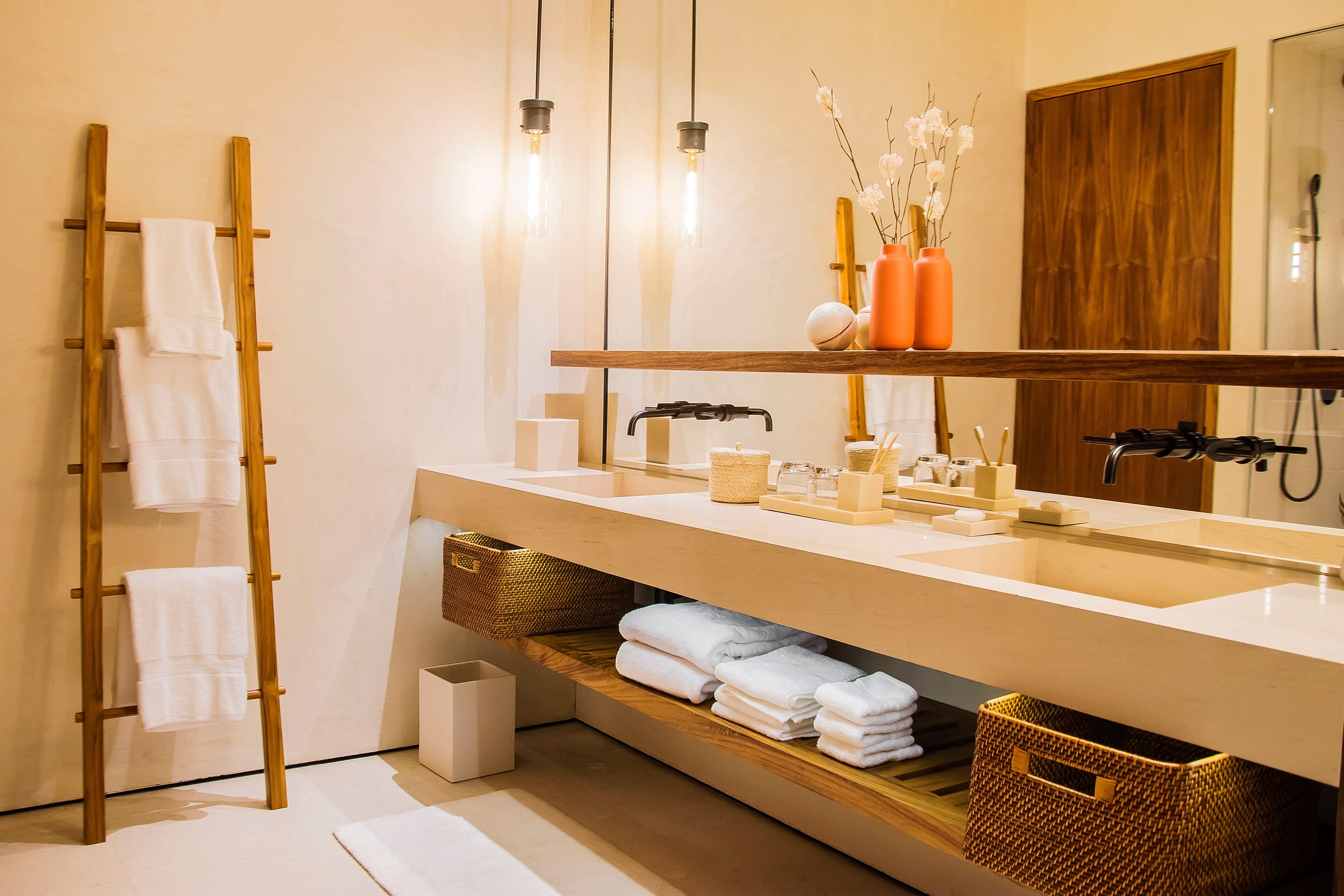 Un baño moderno con una escalera de madera, un espejo grande y un mueble de tocador con cestas de almacenamiento.