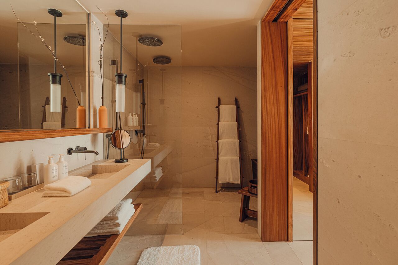 A modern bathroom with a large mirror, two sinks, a shower area, and a wooden vanity.