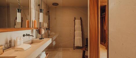 A modern bathroom with a large mirror, two sinks, a shower area, and a wooden vanity.