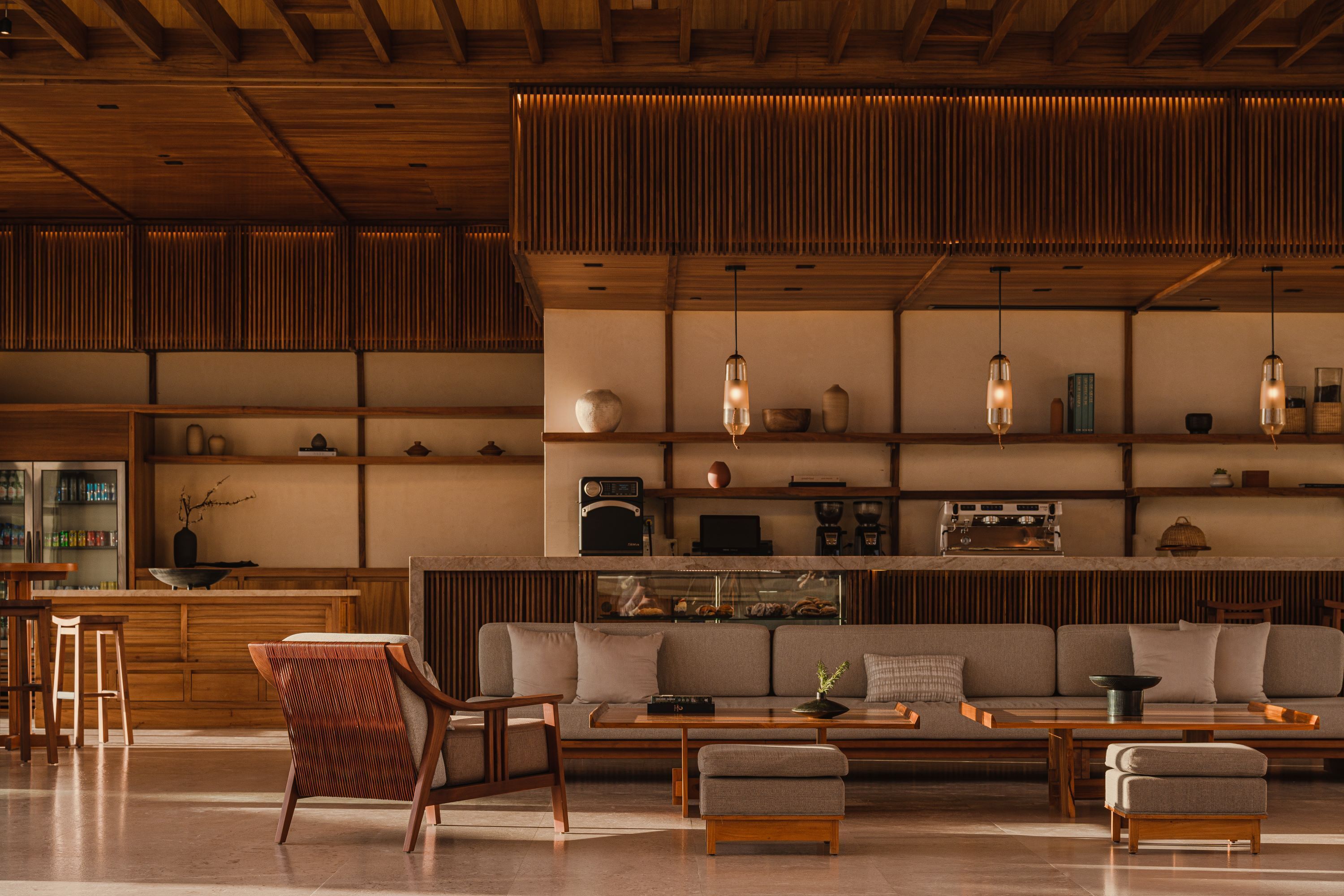 Una sala de estar moderna con techo de madera, un sofá, una mesa de centro y una zona de bar con taburetes.