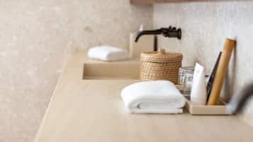 Un baño con encimera de madera, una cesta de mimbre, una toalla doblada, un dispensador de jabón y un rastrillo.