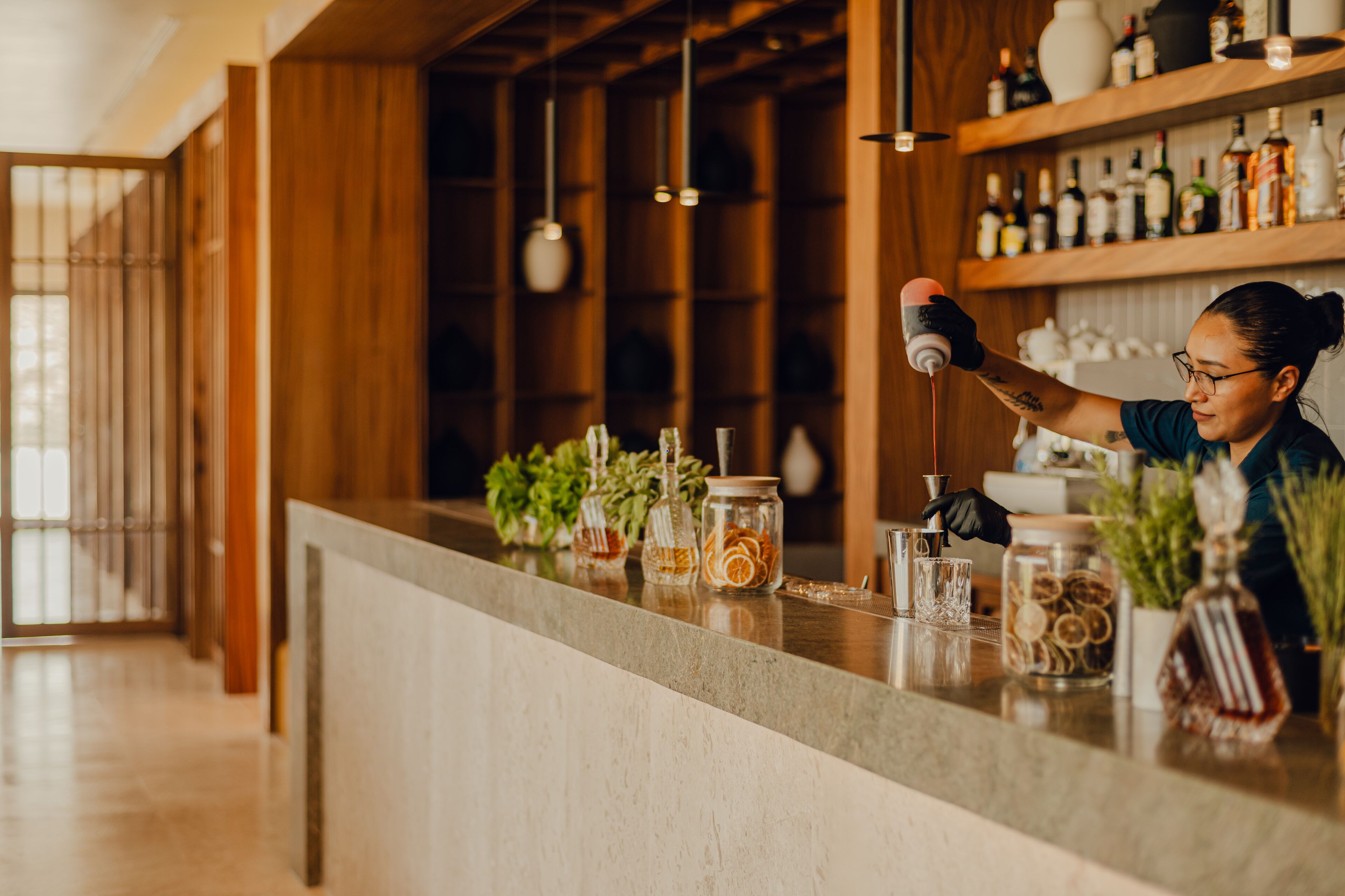 A bar area with a counter, shelves with bottles, and jars with dried fruits.