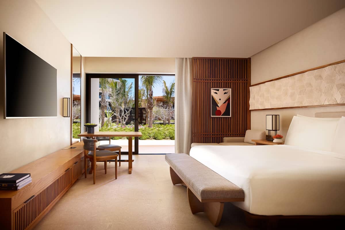 A modern hotel room with a large bed, a desk, and a TV.