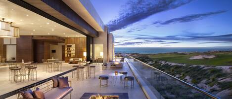 Un área de lounge exterior moderna con un brasero, asientos y vistas al campo de golf.