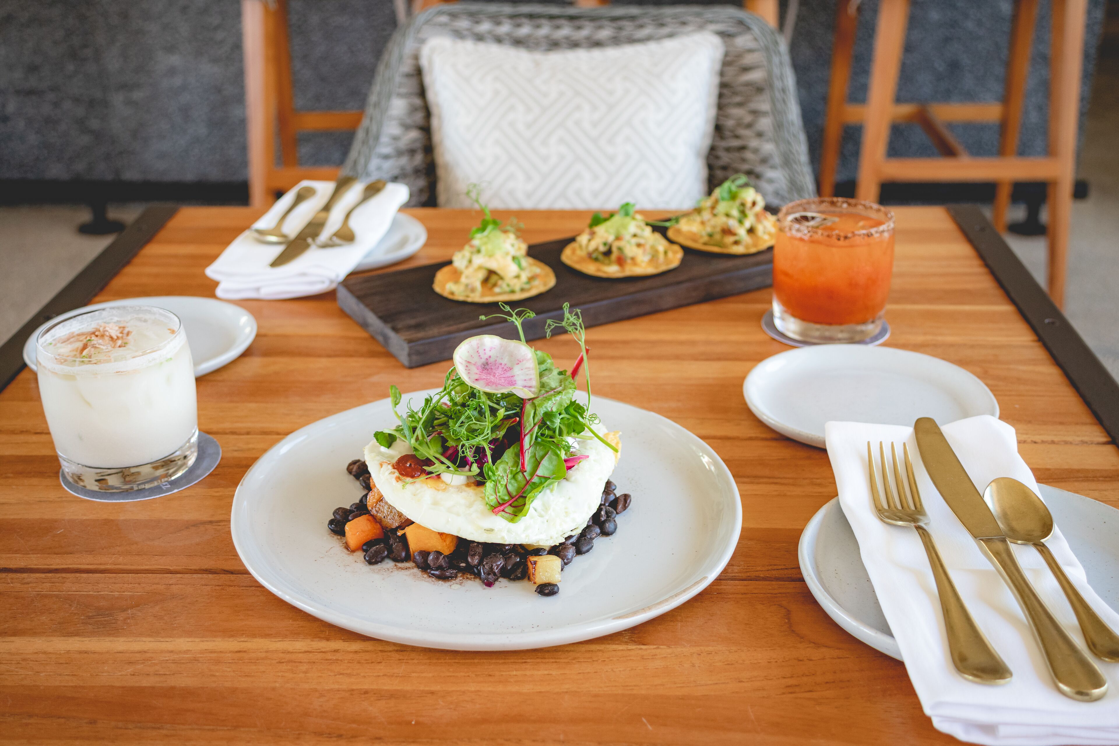 A dining table with plates of food, a glass of juice, and cutlery.
