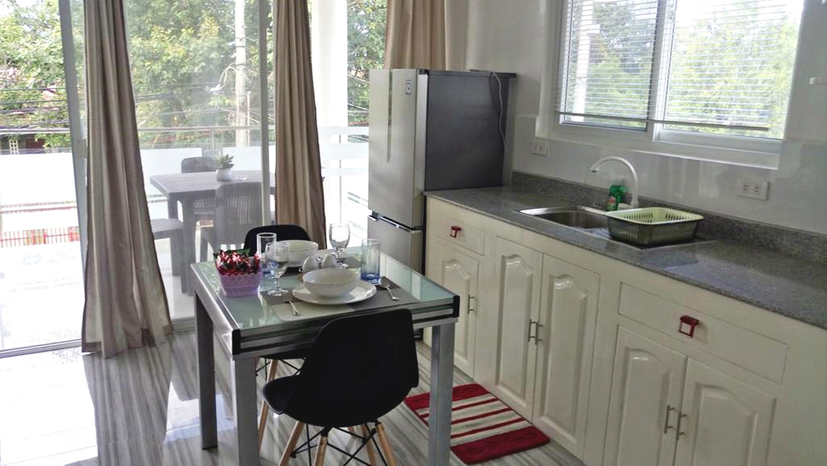 A compact kitchen with a dining area, a refrigerator, a sink, and a window with blinds.