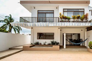 Una casa moderna de dos pisos con balcón, hamaca y zona de patio.