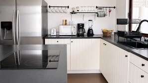 A modern kitchen with a stainless steel refrigerator, a built-in oven, a microwave, a coffee maker, and a blender. - Flip Flop House (Puerto Villamil)