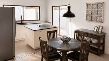 Una cocina moderna con comedor, refrigerador, pileta e iluminación colgante.