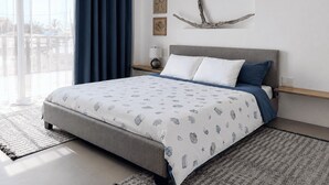 A modern bedroom with a bed, curtains, wall art, and a view through a window. - Flip Flop House (Puerto Villamil)