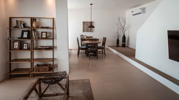 A modern living room with a dining area, featuring a wooden bookshelf, a dining table with chairs, and a hanging light fixture. - Flip Flop House (Puerto Villamil)