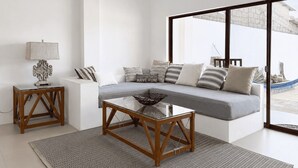 A modern living room with a glass coffee table, a sofa with striped cushions, and a view of the outdoors. - Flip Flop House (Puerto Villamil)