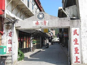 A narrow street with shops on either side, a sign with Chinese characters, and a bicycle parked on the sidewalk. - Yes Sir Homestay - Hostel (Nangan)