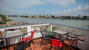 Une terrasse avec des places assises extérieures et une vue sur une rivière où naviguent des bateaux.