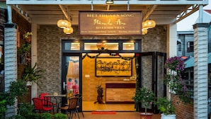 L'entrée de la villa Biet Thu Vien Song Riverside se distingue par une enseigne en bois, un comptoir d'accueil et des plantes en pot.