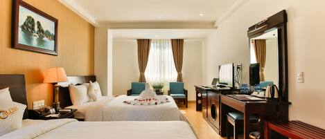 A hotel room with two beds, a desk with a computer, a mirror, and a window with curtains.