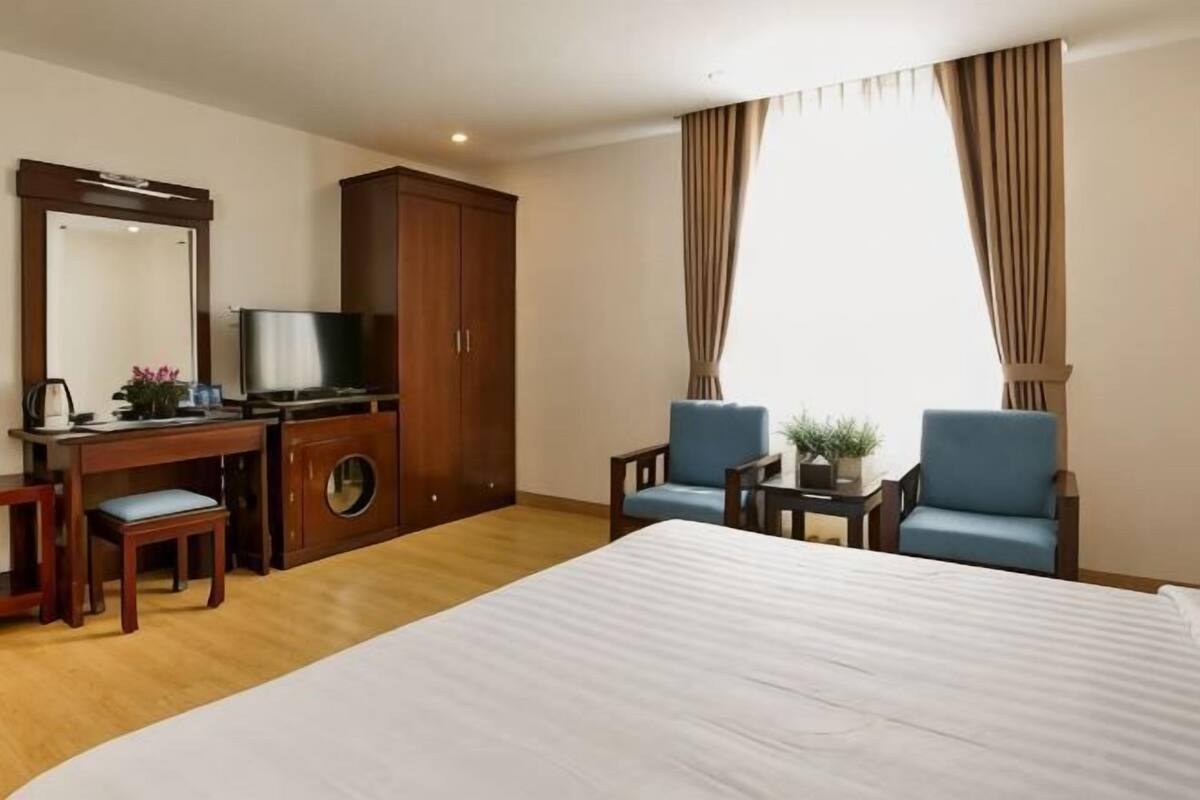 Una habitación de hotel con cama, escritorio, televisión y dos sillas.