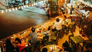 A crowded outdoor dining area with tables and chairs, surrounded by a railing. - TravelBox Dorm Sweet Dorm - Hostel (Hanoi)