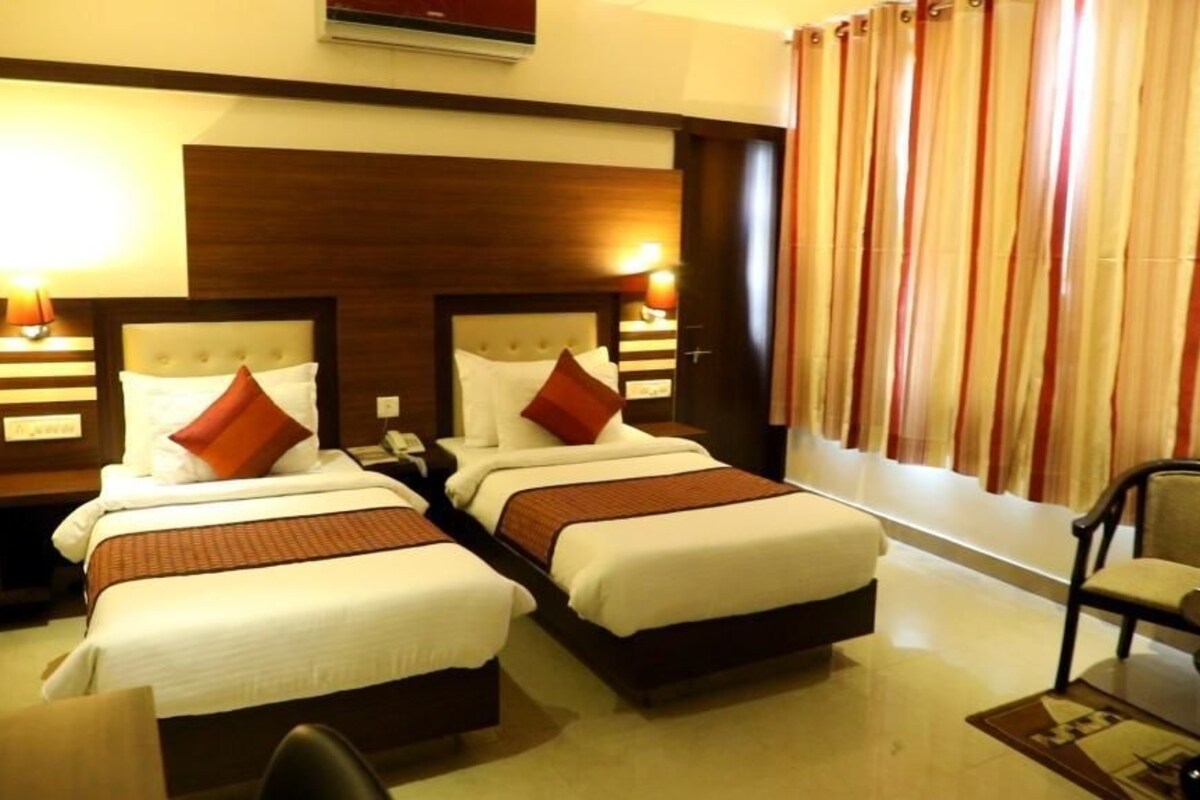 A hotel room with two beds, a desk, and a chair.