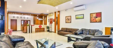 A modern hotel lobby with leather sofas, a reception desk, and artwork on the walls.