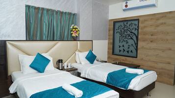 Habitación de hotel con dos camas, un panel decorativo de madera, una obra de arte enmarcada y un aire acondicionado instalado en la pared.