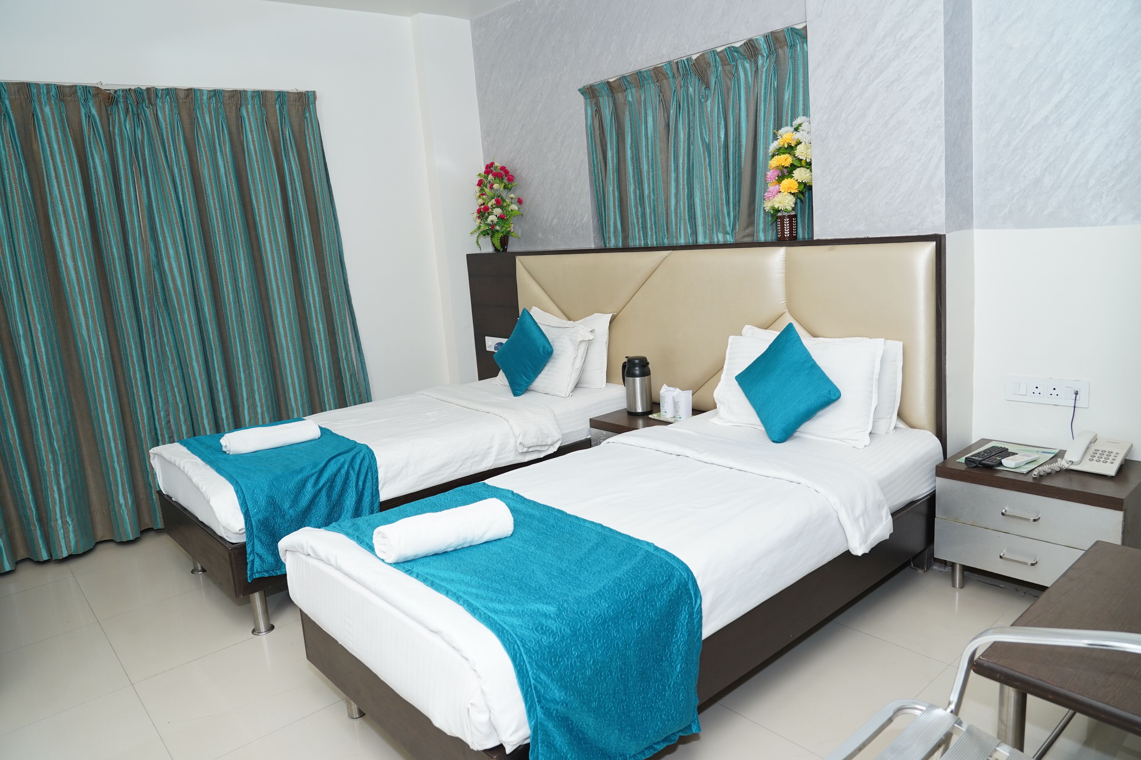 A hotel room with two beds, a desk, a chair, and a nightstand.